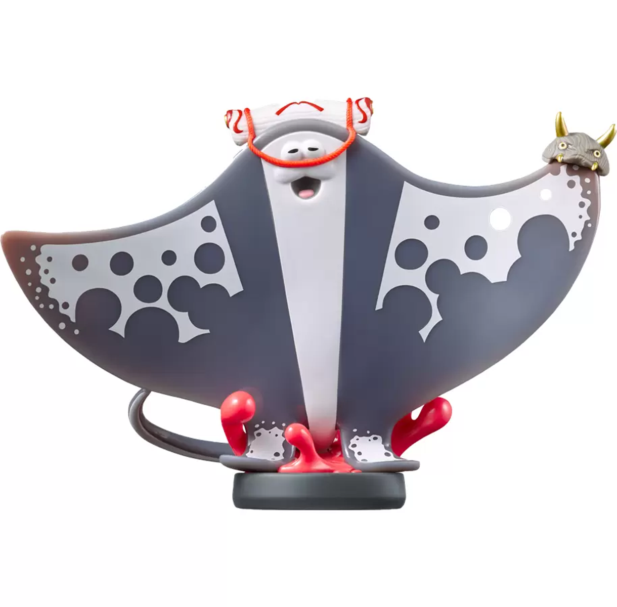 Zabawka płaszczki, biało-szara, z czerwonymi detalami. Stoi na czarnej podstawie. Białe tło.