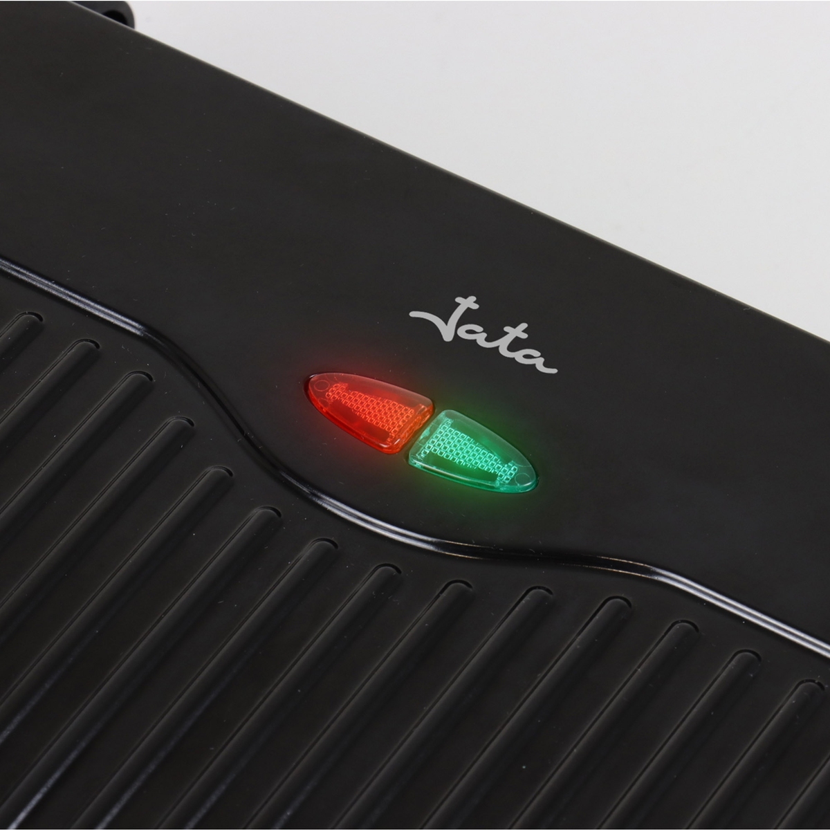 Una parrilla negra con luces indicadoras rojas y verdes. La marca "Jata" está impresa.