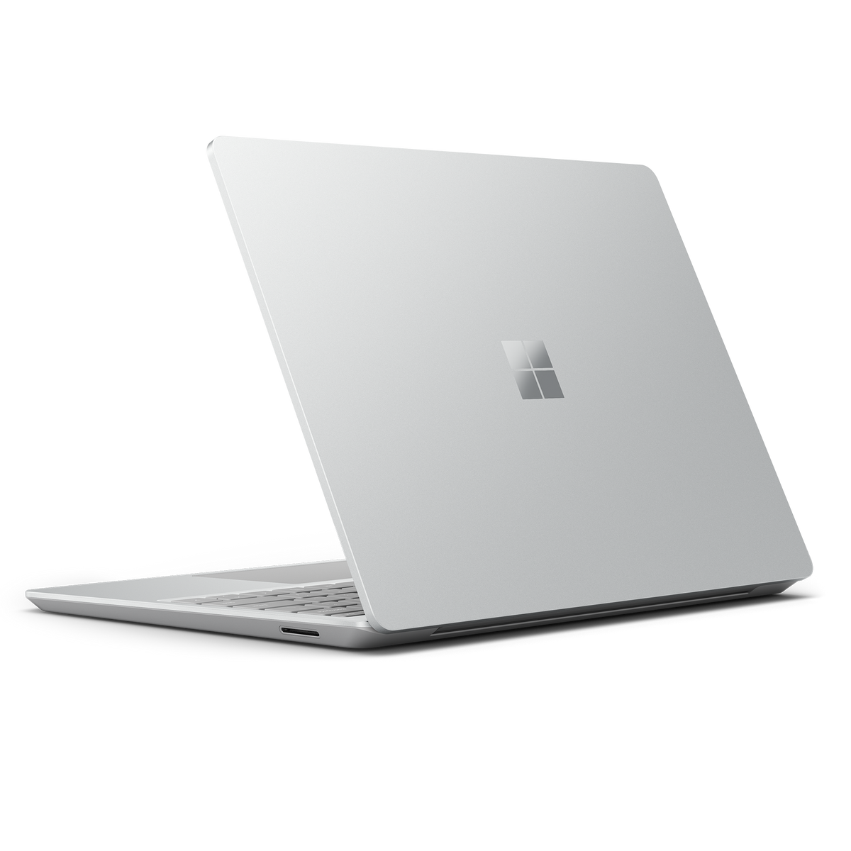 Portátil plateado, cerrado, en ángulo. El logotipo de Microsoft es visible en la tapa.