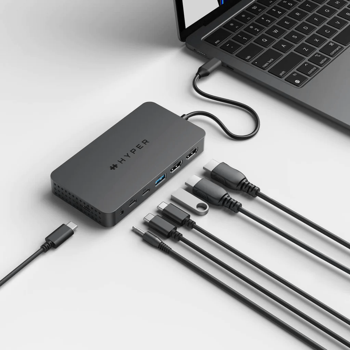 Un laptop collegato a un hub con diversi cavi e un'unità USB.