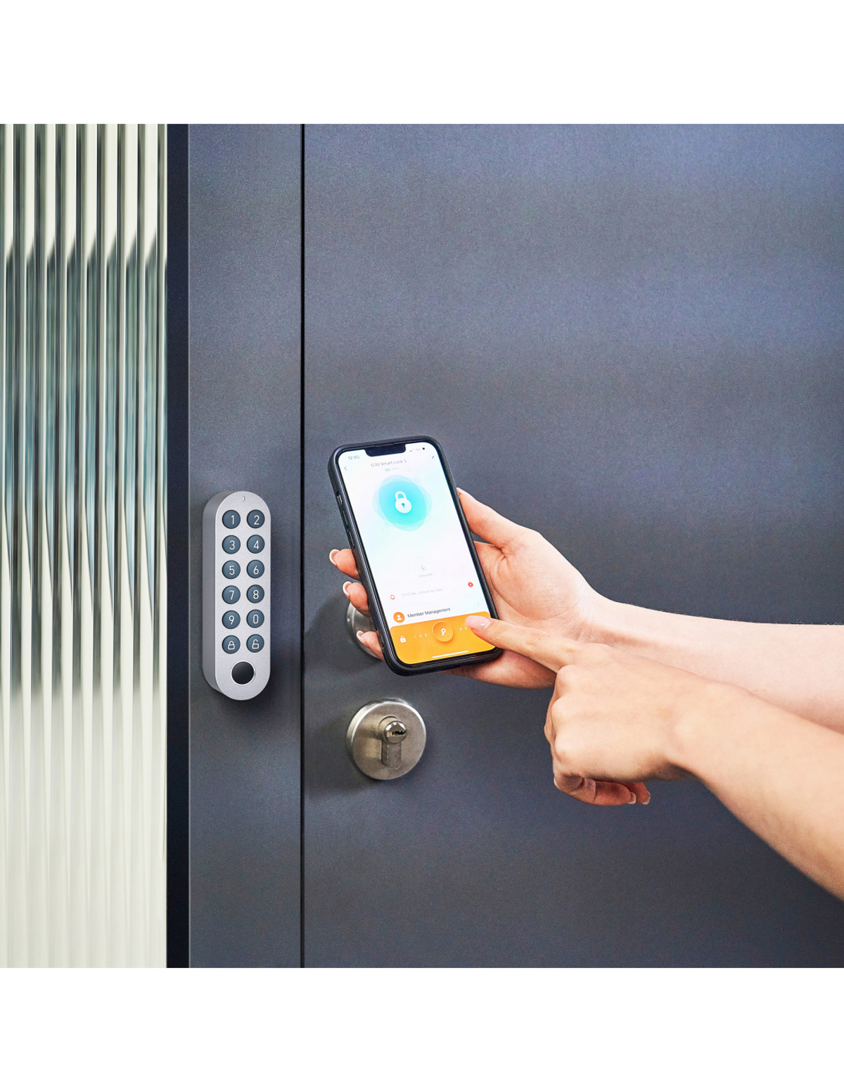 Una persona desbloqueando una puerta con un smartphone. Un teclado está a la izquierda, la puerta es gris.