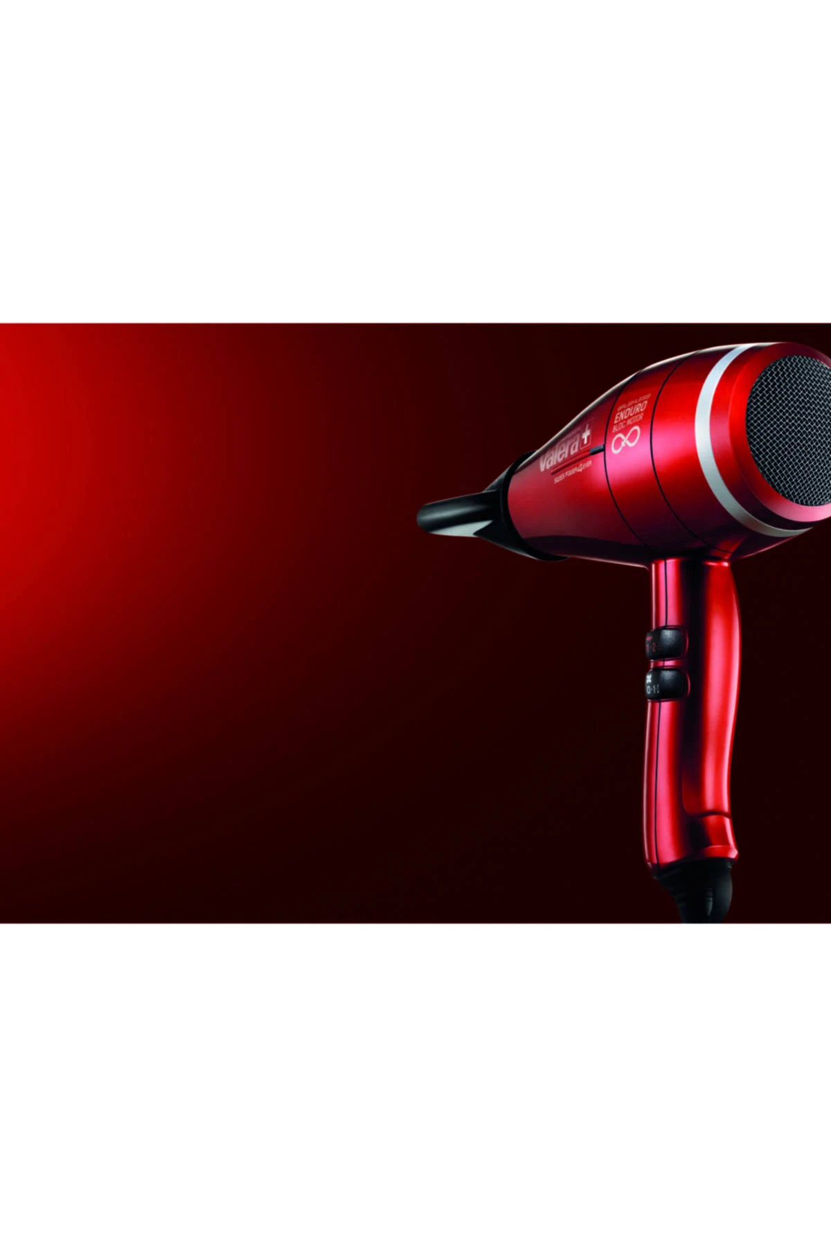 Czerwona suszarka do włosów na ciemnoczerwonym tle. Suszarka umieszczona po prawej stronie kadru.