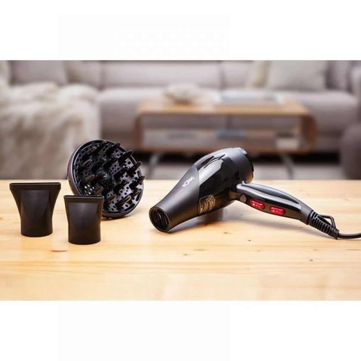 Czarna suszarka do włosów z nasadkami na drewnianej powierzchni. Rozmyte tło.