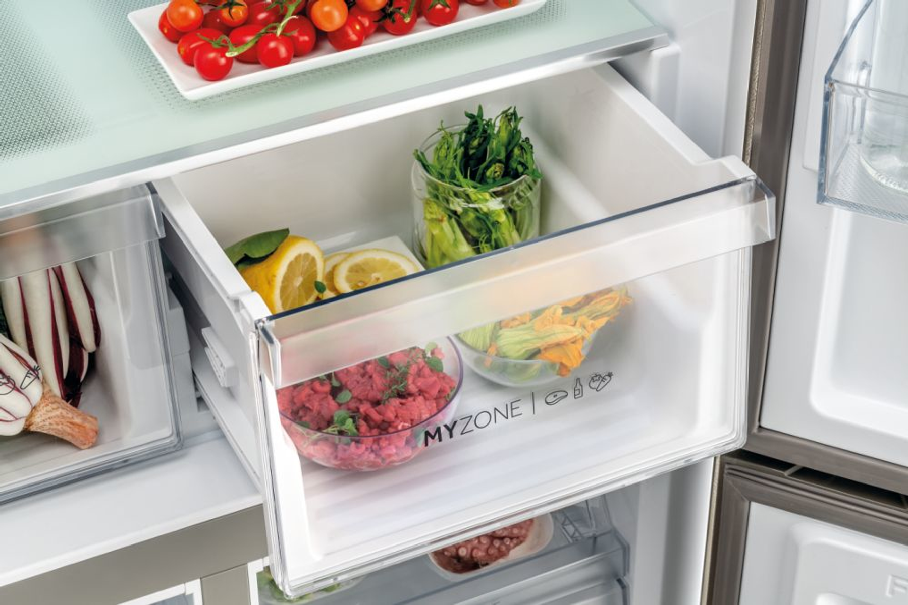 Cajón de refrigerador con verduras frescas, limones y carne. Cajón blanco con recipientes de vidrio.