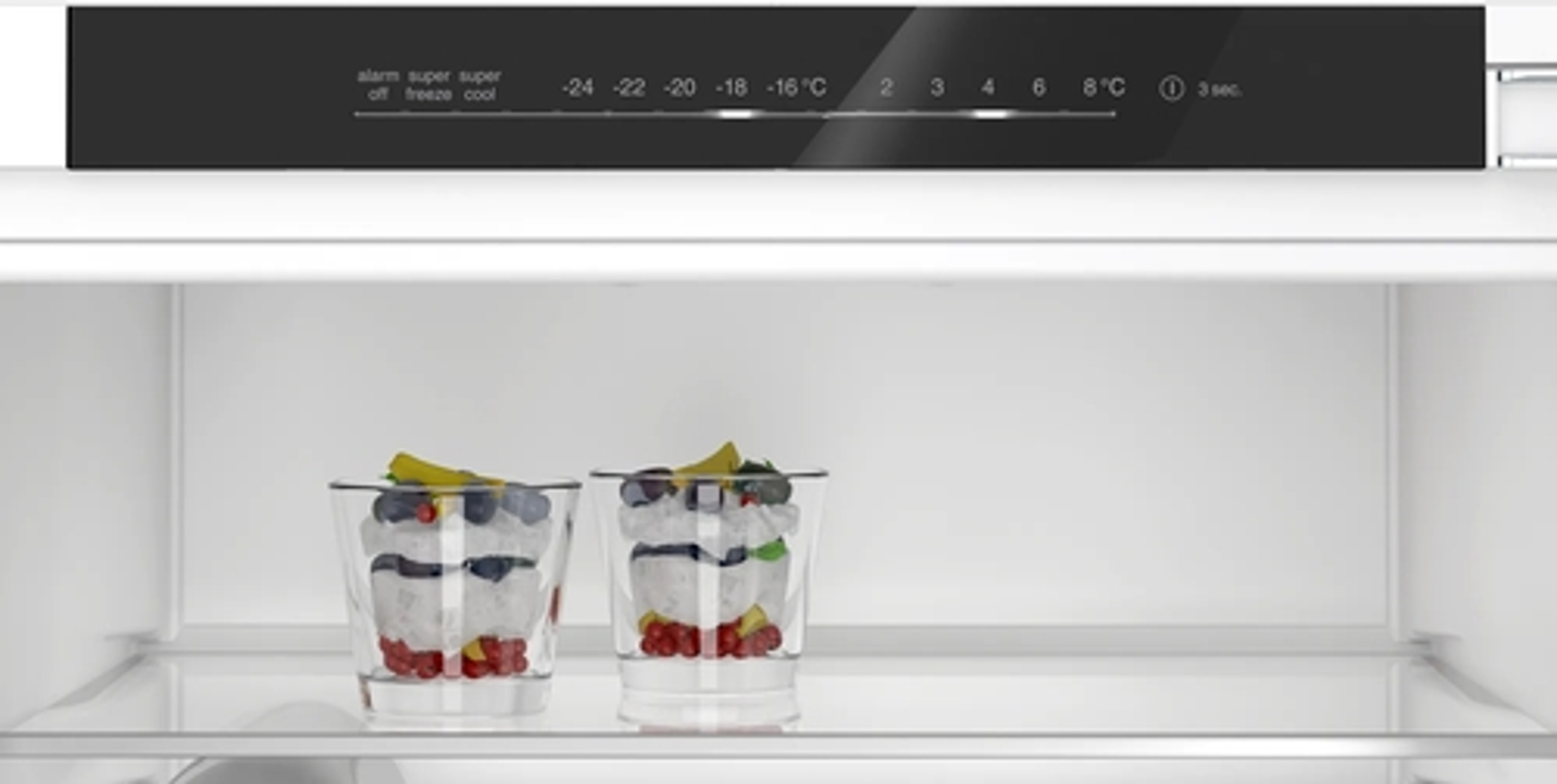 Interior de refrigerador con dos postres en vasos. Panel de temperatura y control en la parte superior.