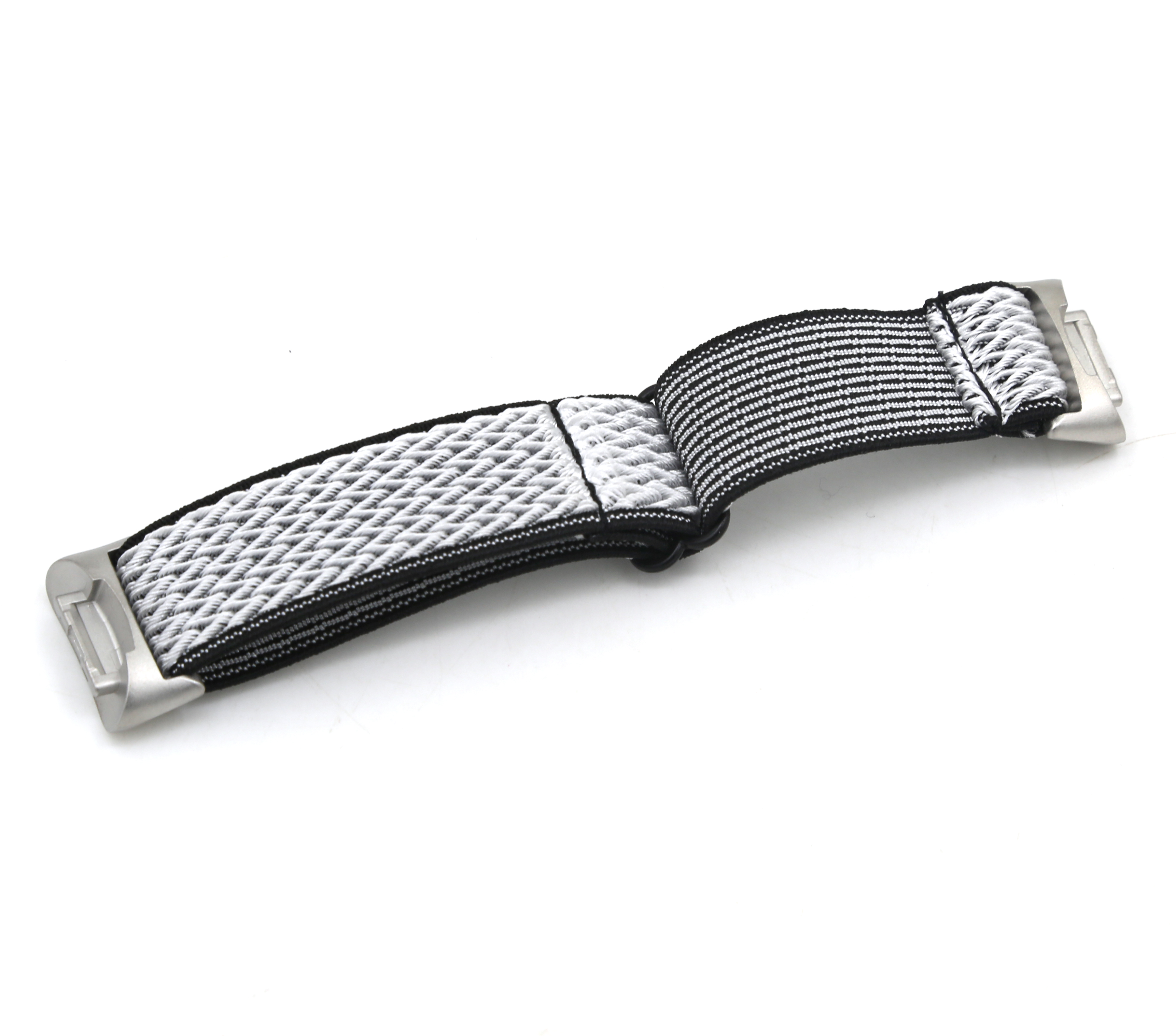 Una correa de reloj con un patrón tejido blanco y negro, sujeta a cierres metálicos plateados, sobre una superficie blanca.