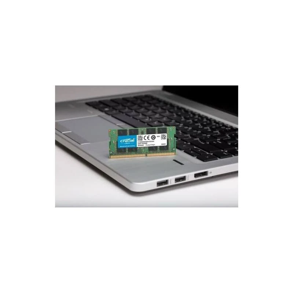 Moduł RAM Crucial leży na klawiaturze laptopa.