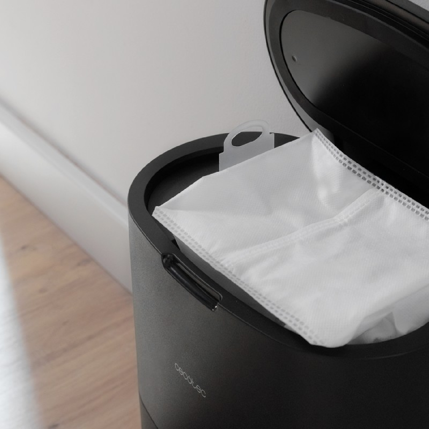 Primo piano del contenitore della polvere di un aspirapolvere nero con un sacchetto bianco all'interno.
