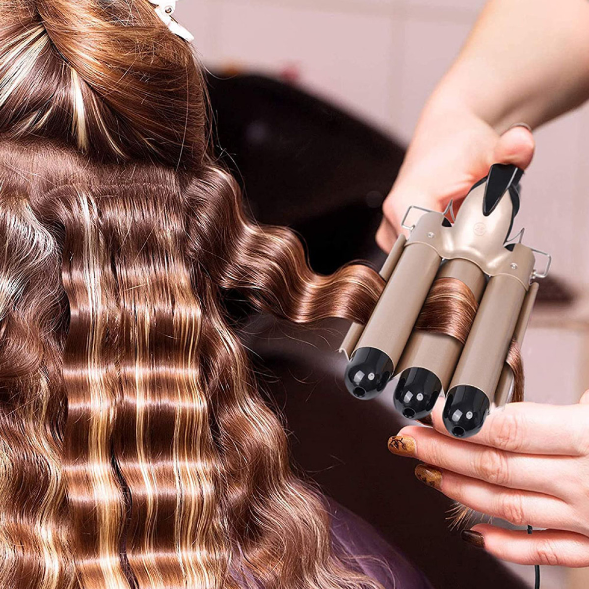 Eine Person verwendet einen Lockenstab auf dem Haar einer Frau, wodurch wellige Locken entstehen.
