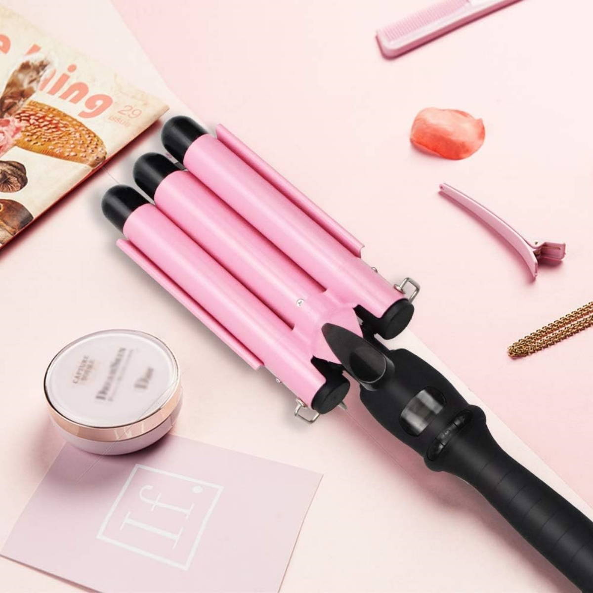 Rosa Haarwellengerät auf rosa Hintergrund. Kamm, Dior-Kompaktpuder und Haarspange sind ebenfalls vorhanden.