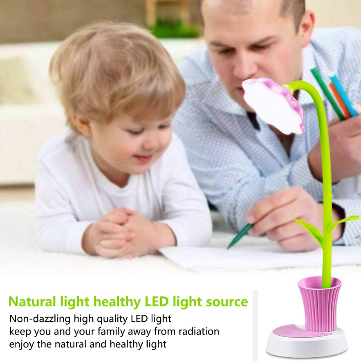 Ein Kind und ein Mann schreiben mit einer blütenförmigen LED-Lampe. Die Lampe ist rosa und grün, mit weißem Sockel.