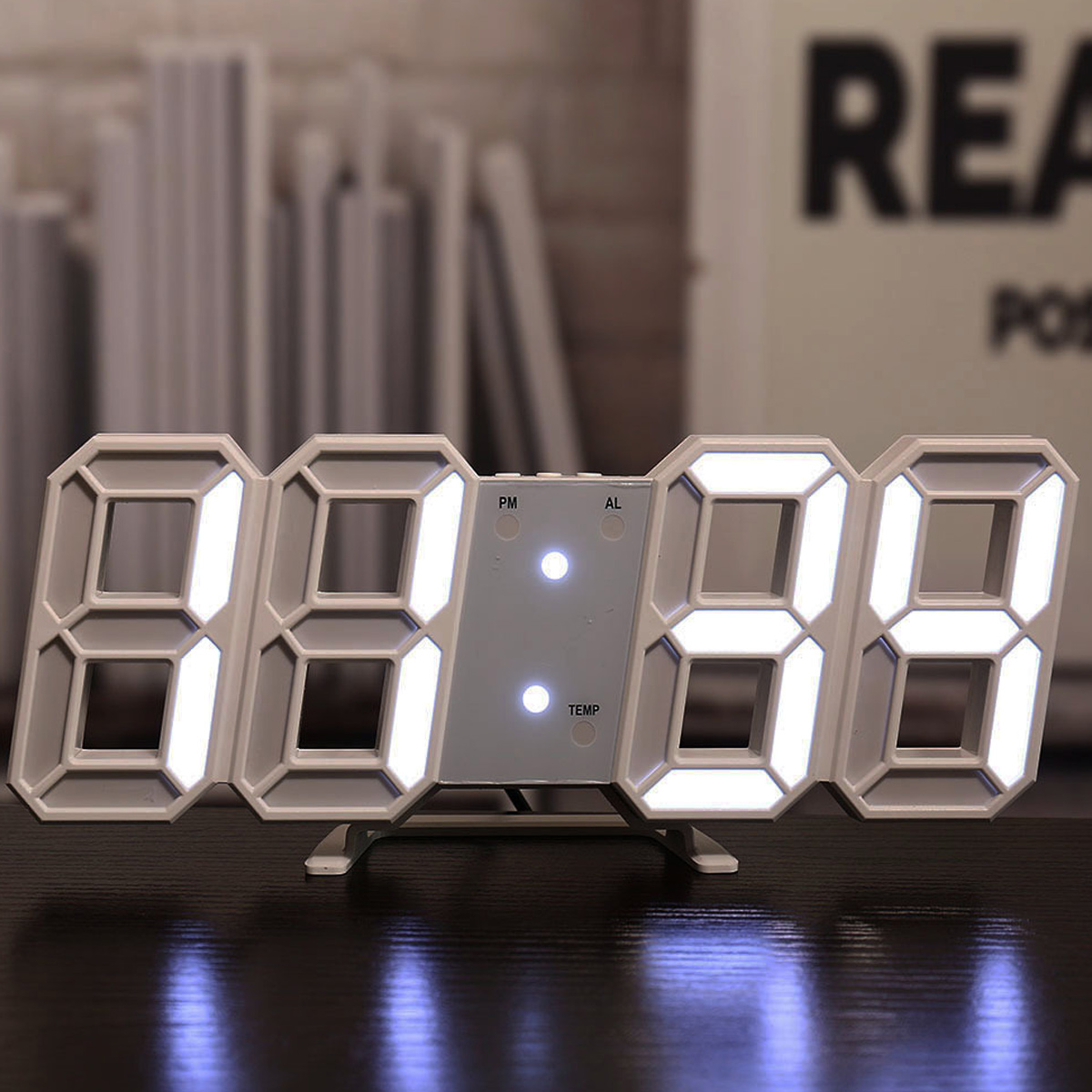 Weiße Digitaluhr. Die Zahlen sind weiß auf schwarzem Hintergrund. Die Uhr steht auf dunkler Oberfläche.