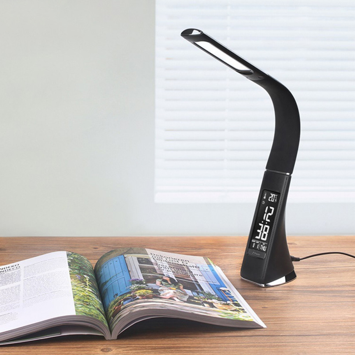 Eine schwarze Schreibtischlampe mit Digitalanzeige, auf einem Holzschreibtisch, mit einem Magazin in der Nähe.