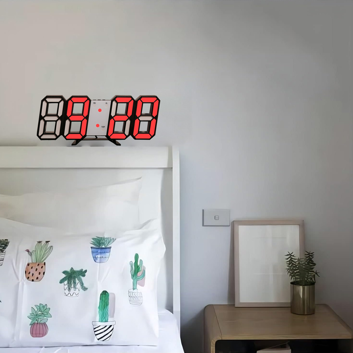 Digitaluhr mit roten Zahlen, an einer weißen Wand über einem Bett mit Kissen.