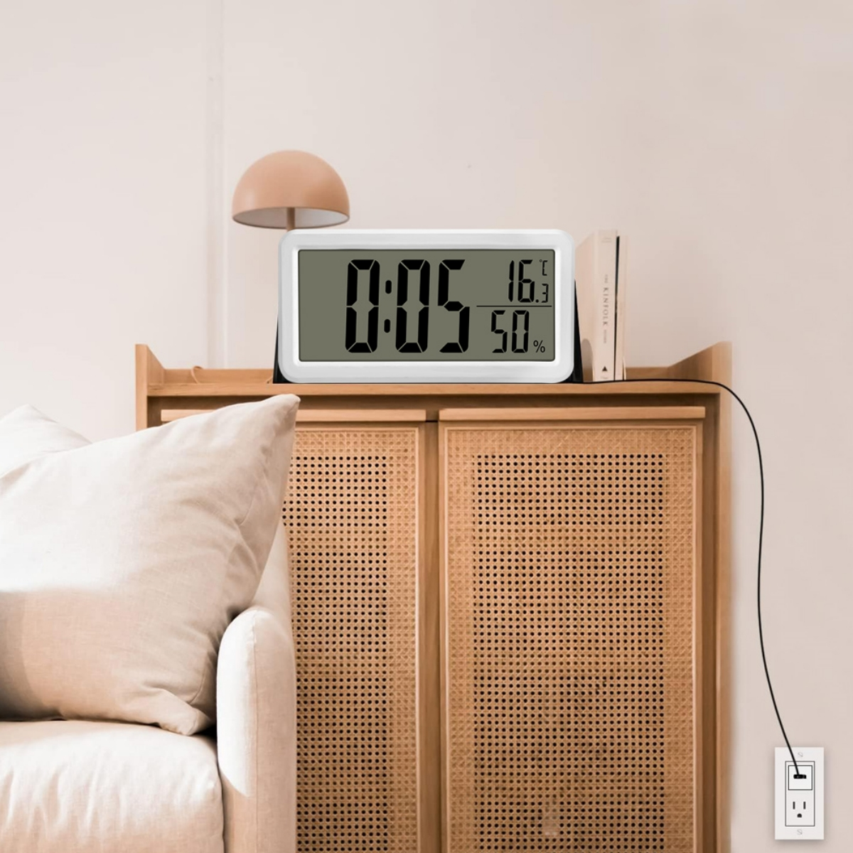 Digitaluhr auf einem Schrank. Zeigt Zeit, Temperatur und Luftfeuchtigkeit an.