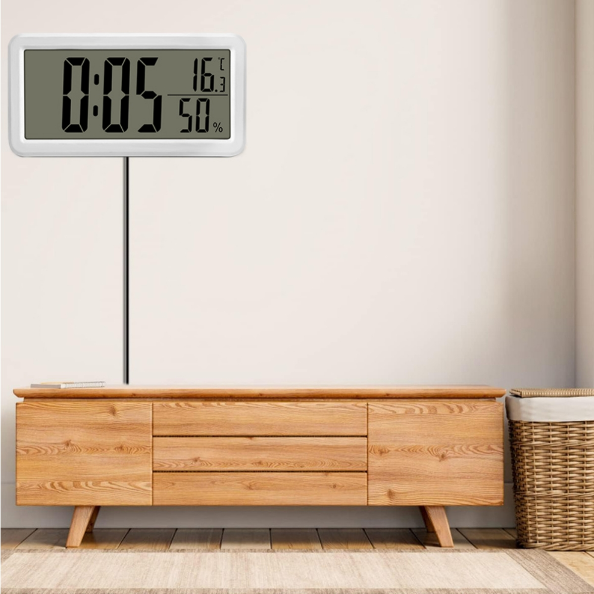 Digitalanzeige mit Temperatur, Luftfeuchtigkeit und Uhrzeit an weißer Wand.
