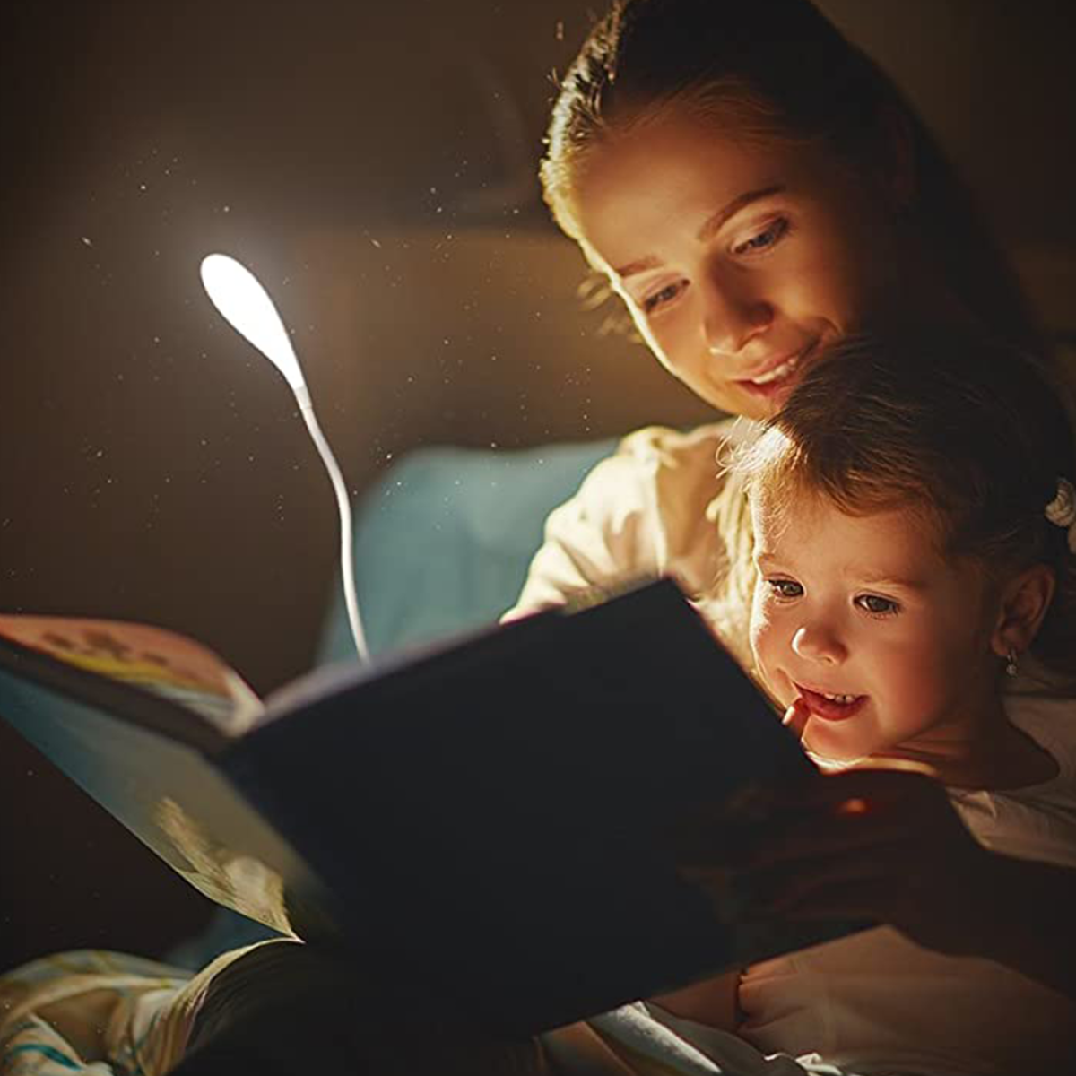 Mutter und Kind lesen gemeinsam ein Buch unter sanftem, weißem Licht.
