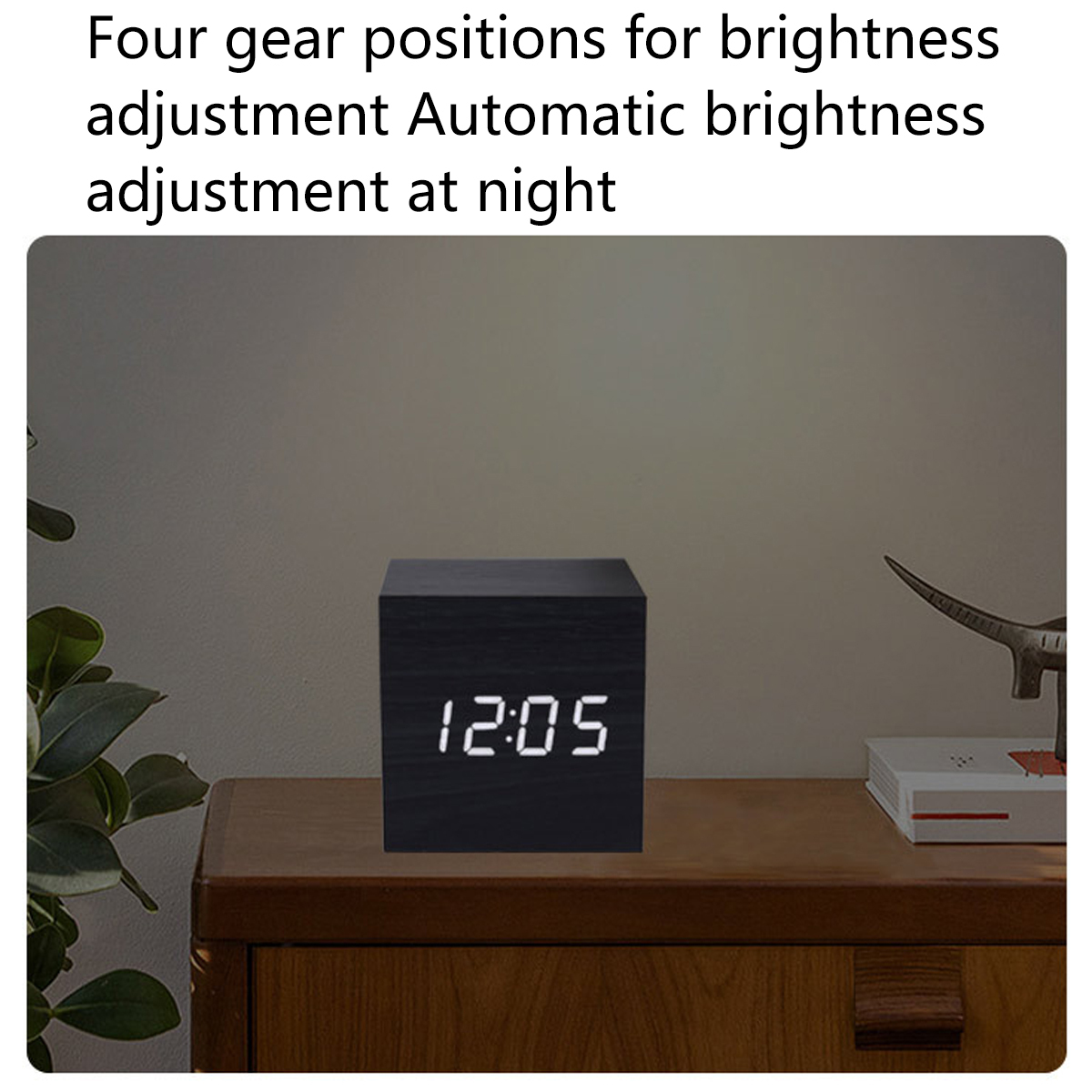 Eine schwarze Holzwürfeluhr, die 12:05 anzeigt, auf einem Holztisch.