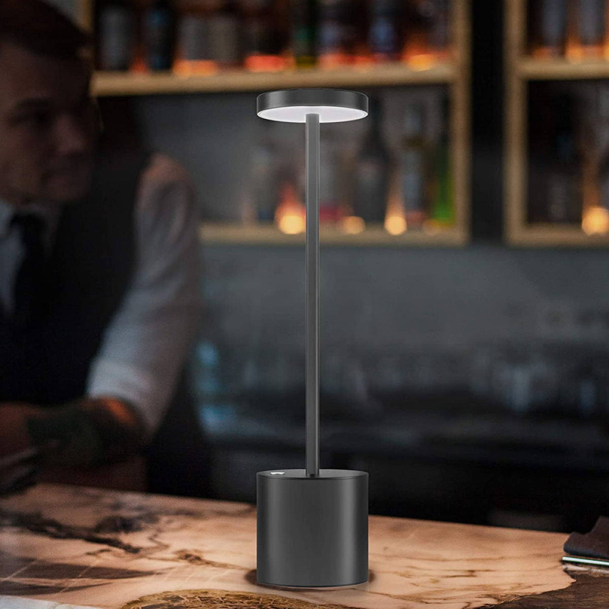 Eine schwarze, moderne Tischlampe mit vertikalem Schaft und kreisförmigem Licht oben.