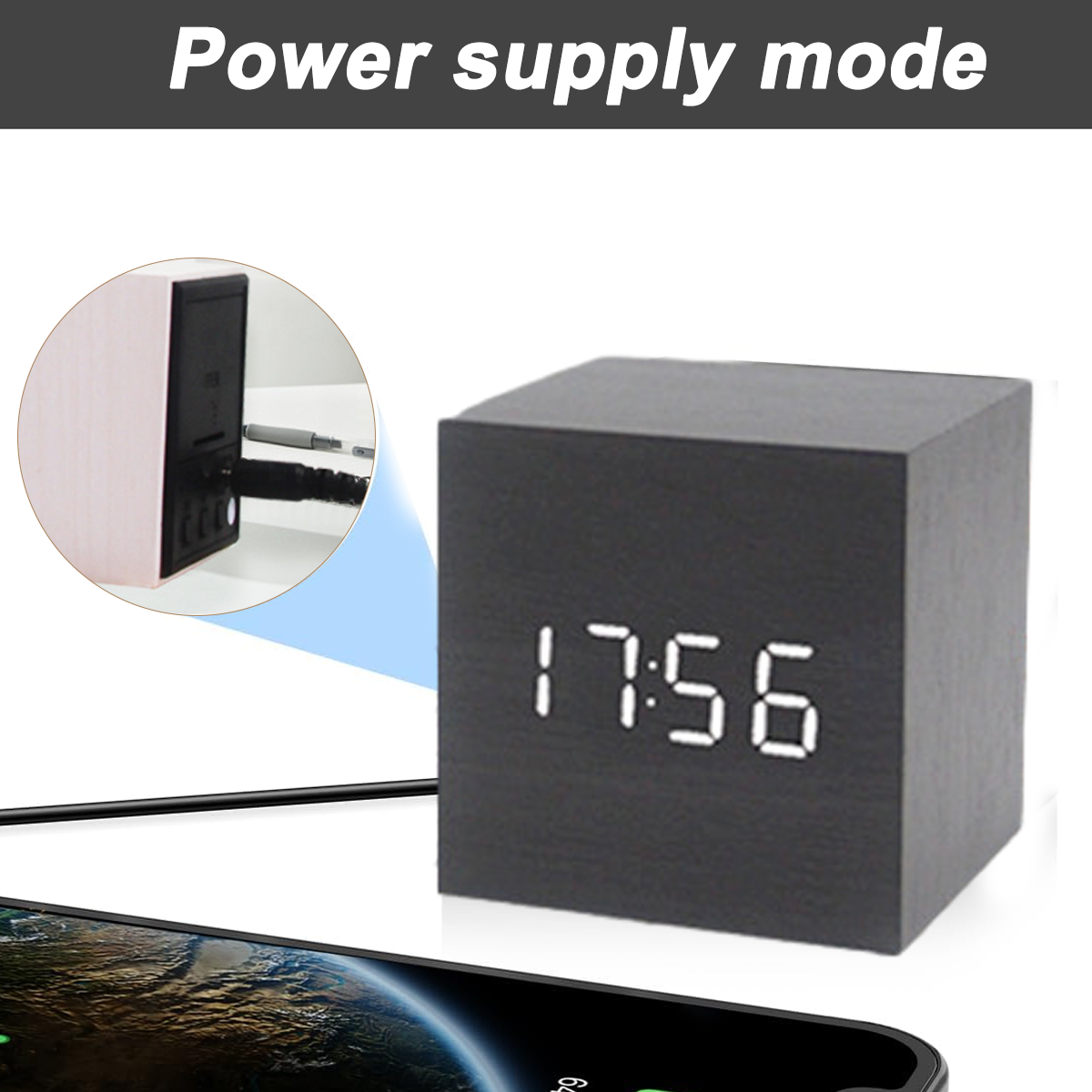 Schwarzer Würfeluhr mit weißen Zahlen, die die Zeit anzeigen. Ein Telefon und ein Ladekabel sind zu sehen.