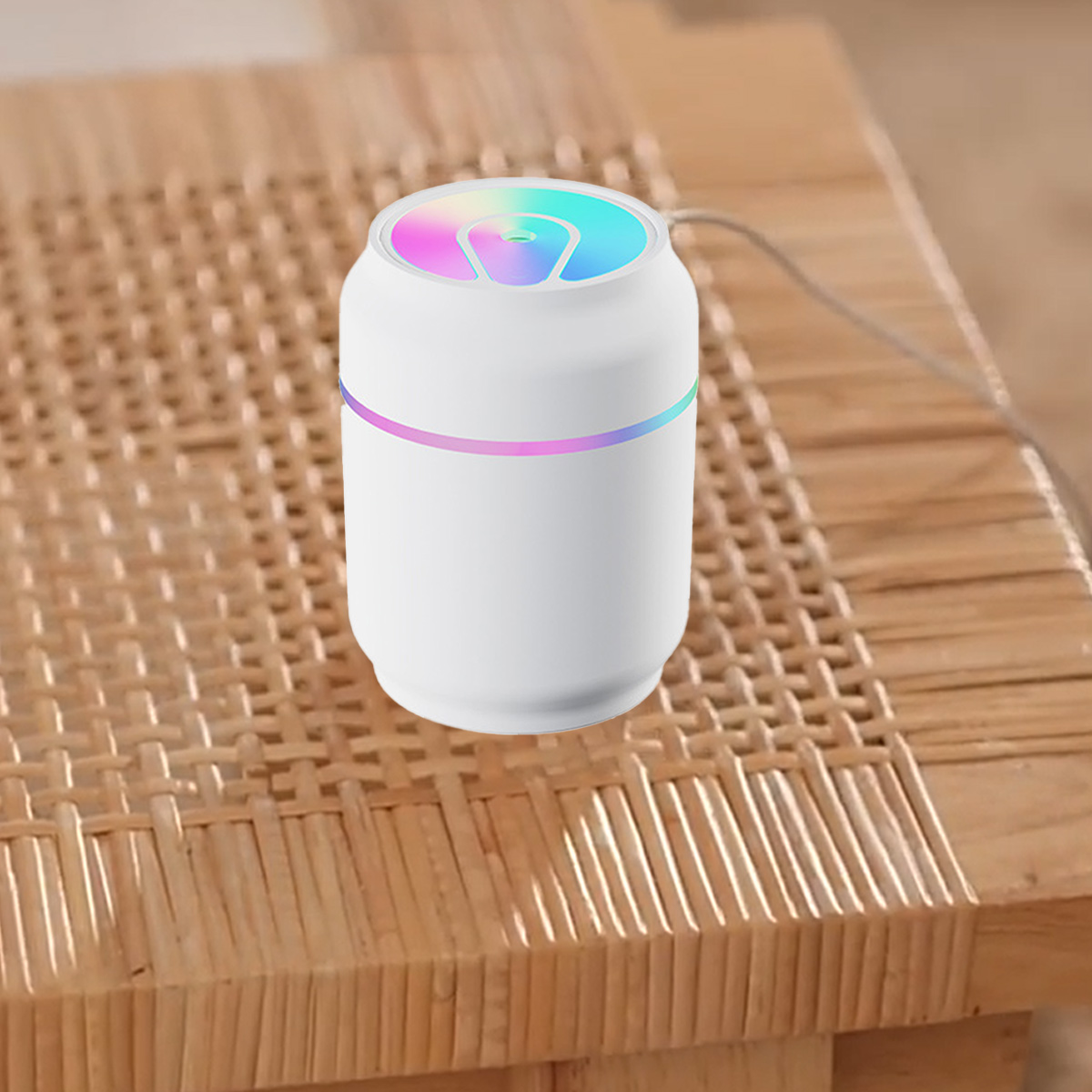 Ein weißer, dosenähnlicher Luftbefeuchter mit farbigem Licht oben. Er steht auf einem Holztisch.