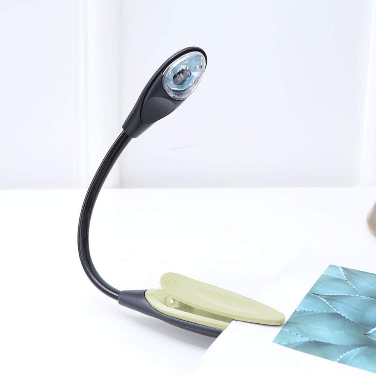 Eine kleine schwarze und grüne Leselampe an Seiten befestigt. Flexibler Hals, Licht an, grüner Clip-Sockel.