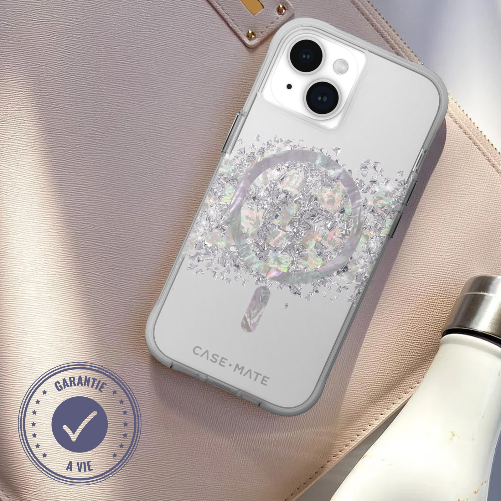 Transparente Handyhülle mit Glitzer, silbernem Ring und weißer Wasserflasche auf rosa Oberfläche.