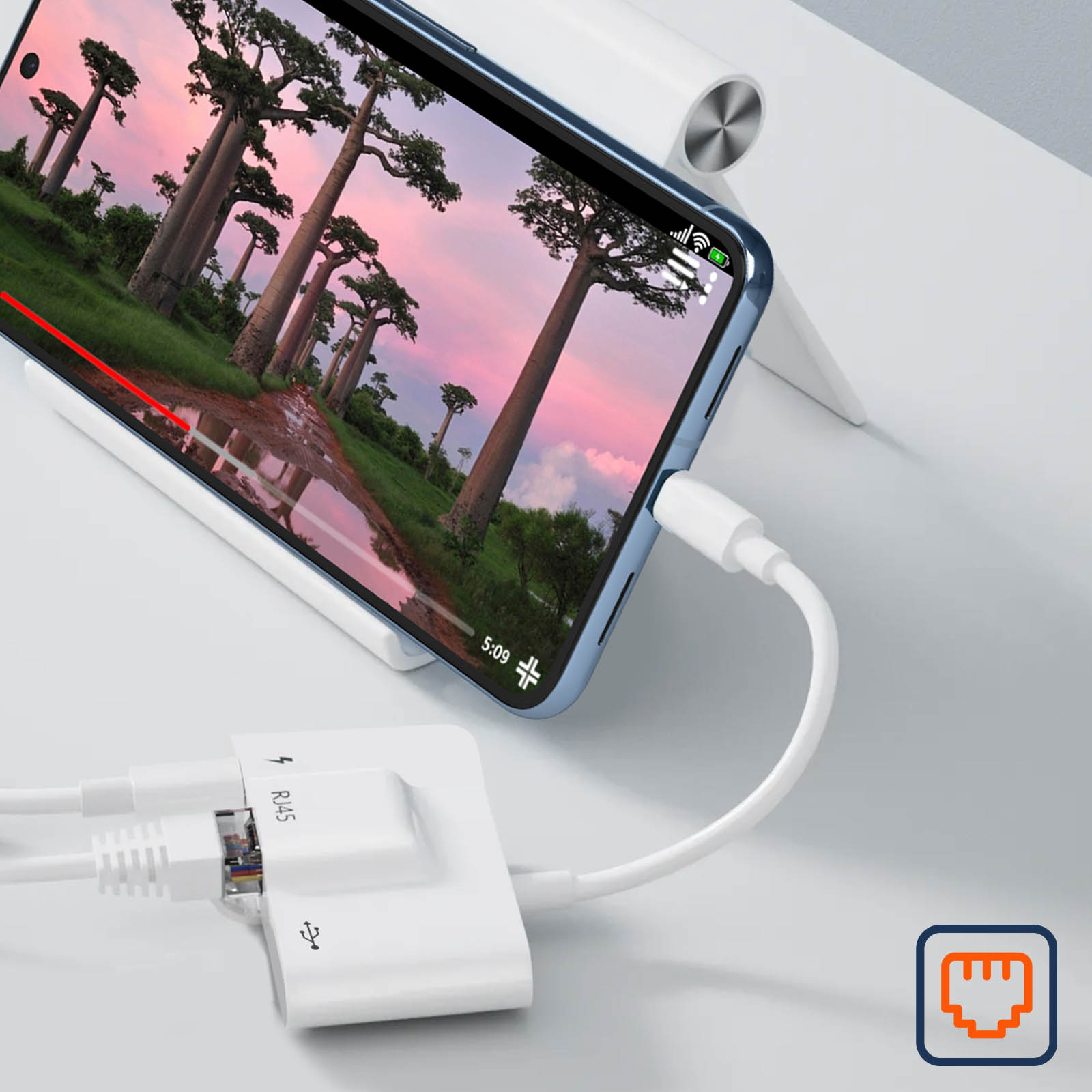 Telefono che mostra video, collegato ad adattatore con Ethernet e USB. Sfondo di alberi Baobab.