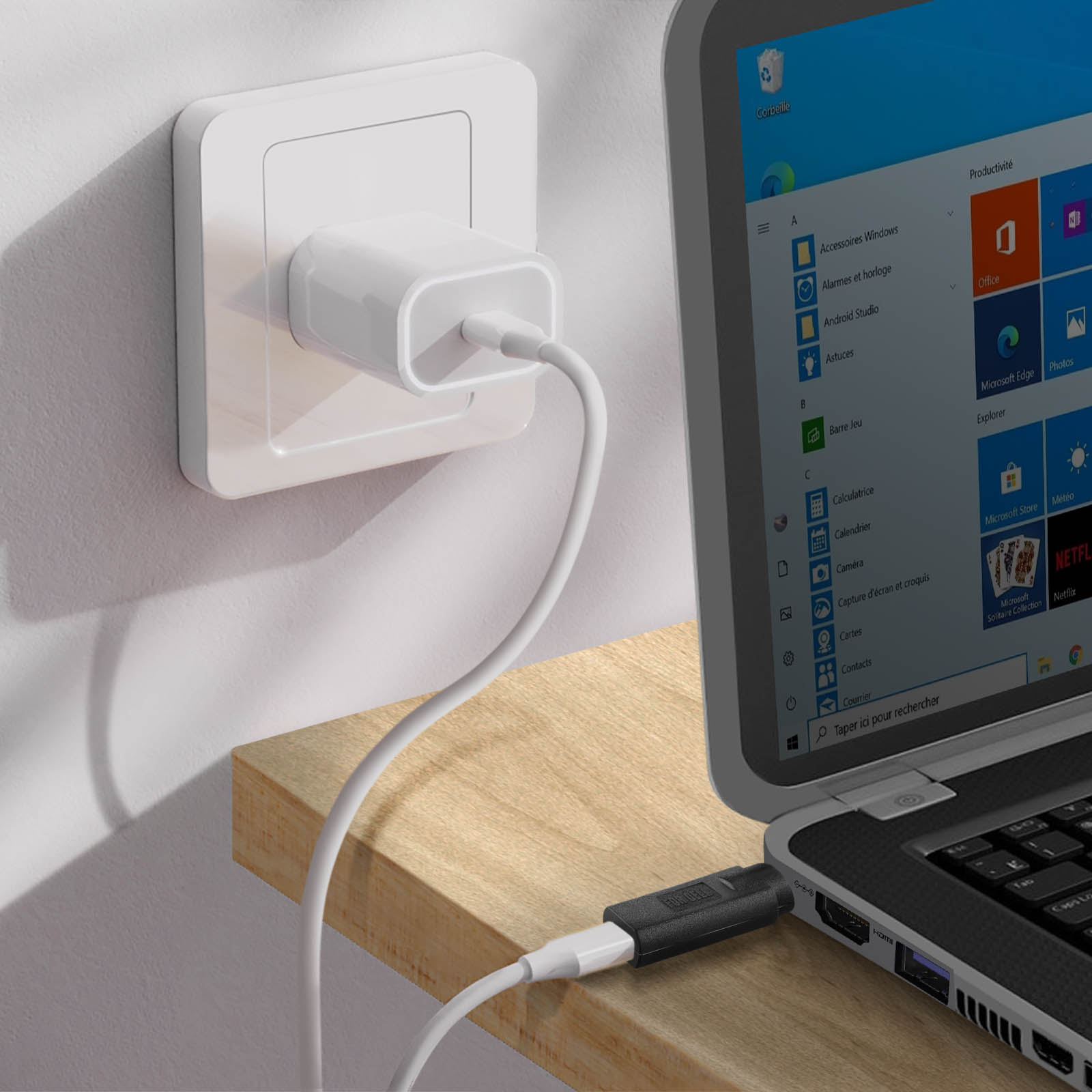 Un caricatore bianco è collegato a una presa a muro, con un cavo collegato a un laptop.