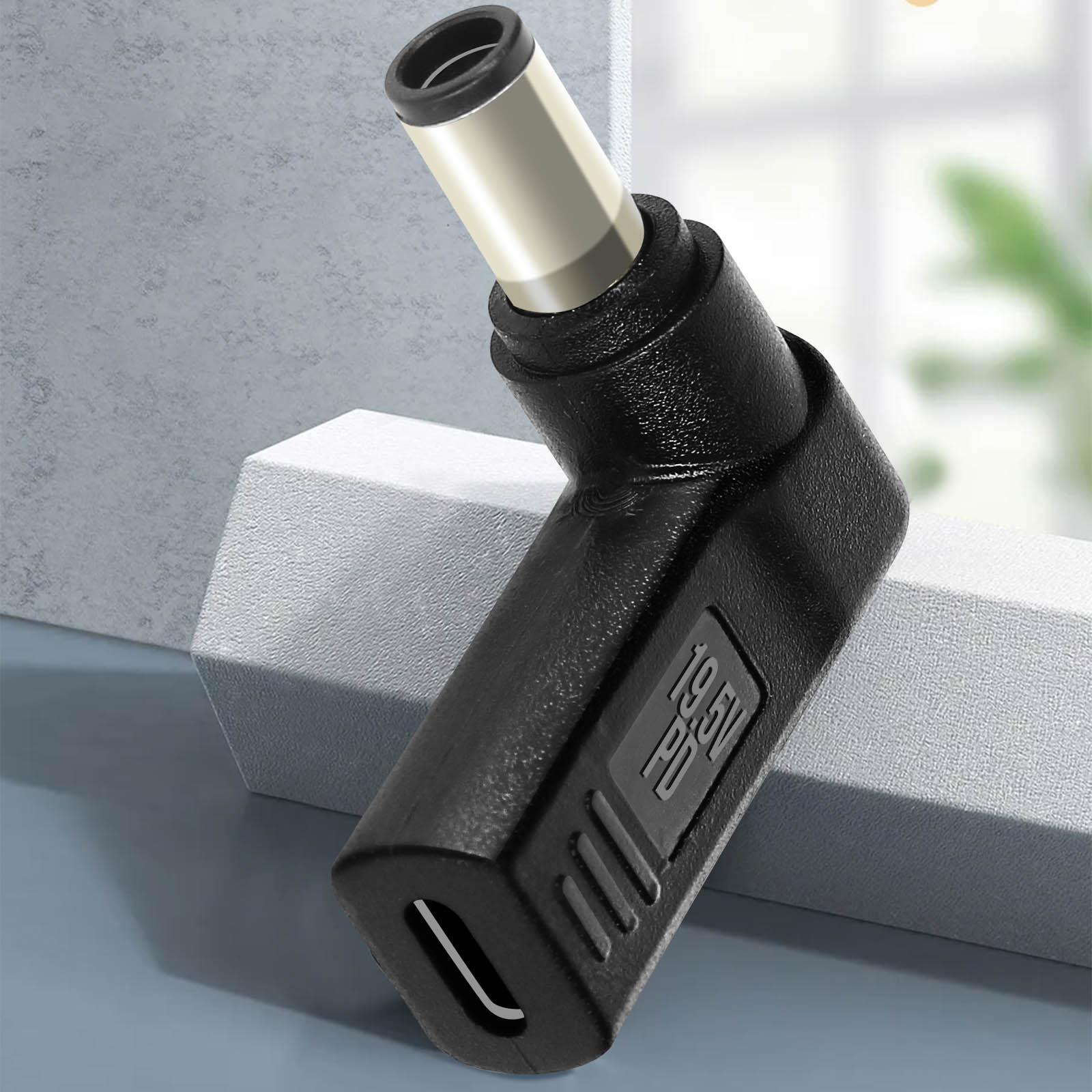 Primo piano di un adattatore di alimentazione nero con etichetta 19,5V PD e porta USB-C.