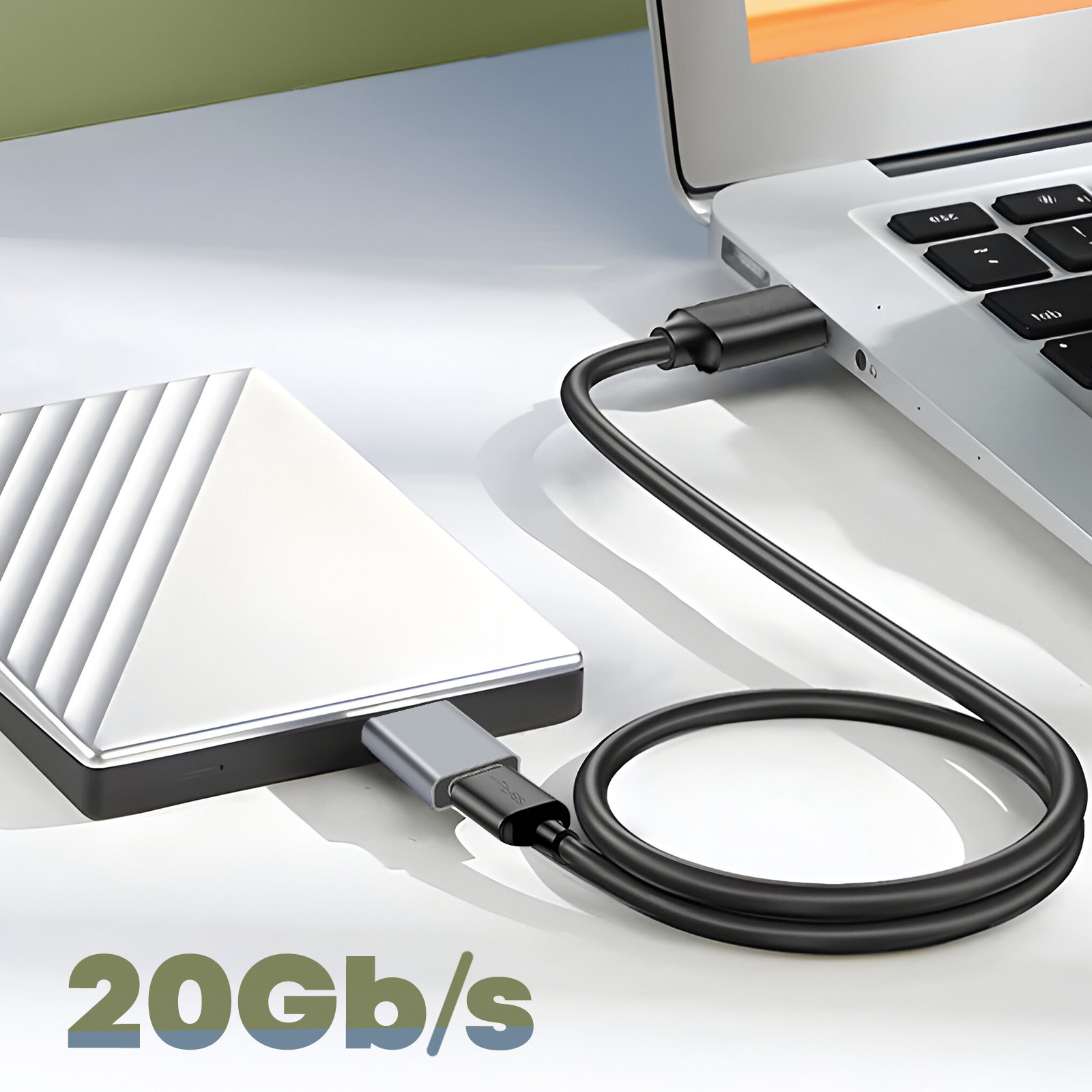 Un cavo nero collega un disco rigido argentato a un laptop. Testo: 20 Gb/s.