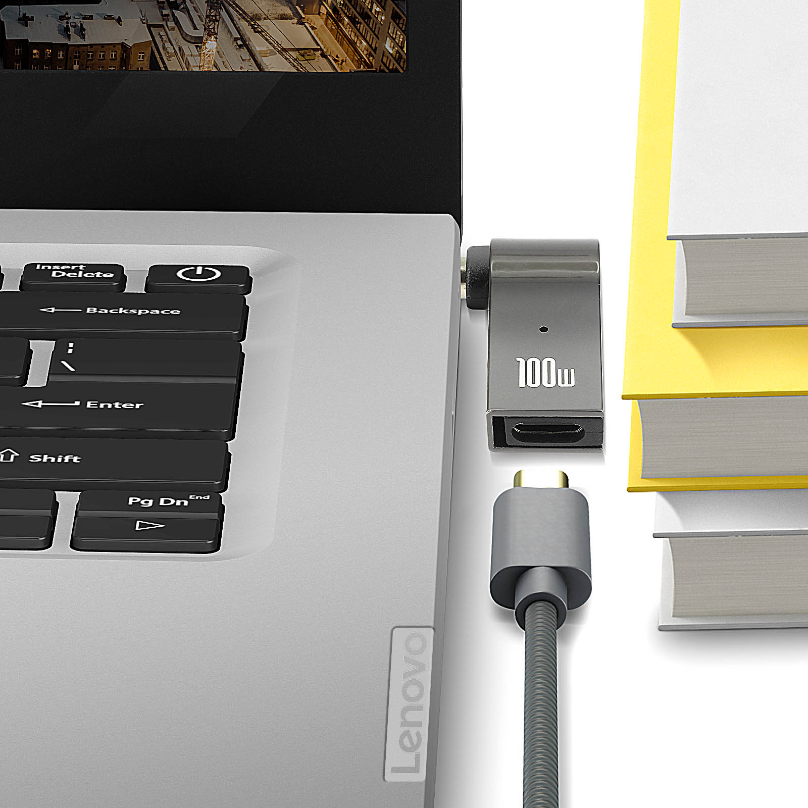 Laptop con adattatore USB-C collegato e cavo. I libri sono sul lato destro.