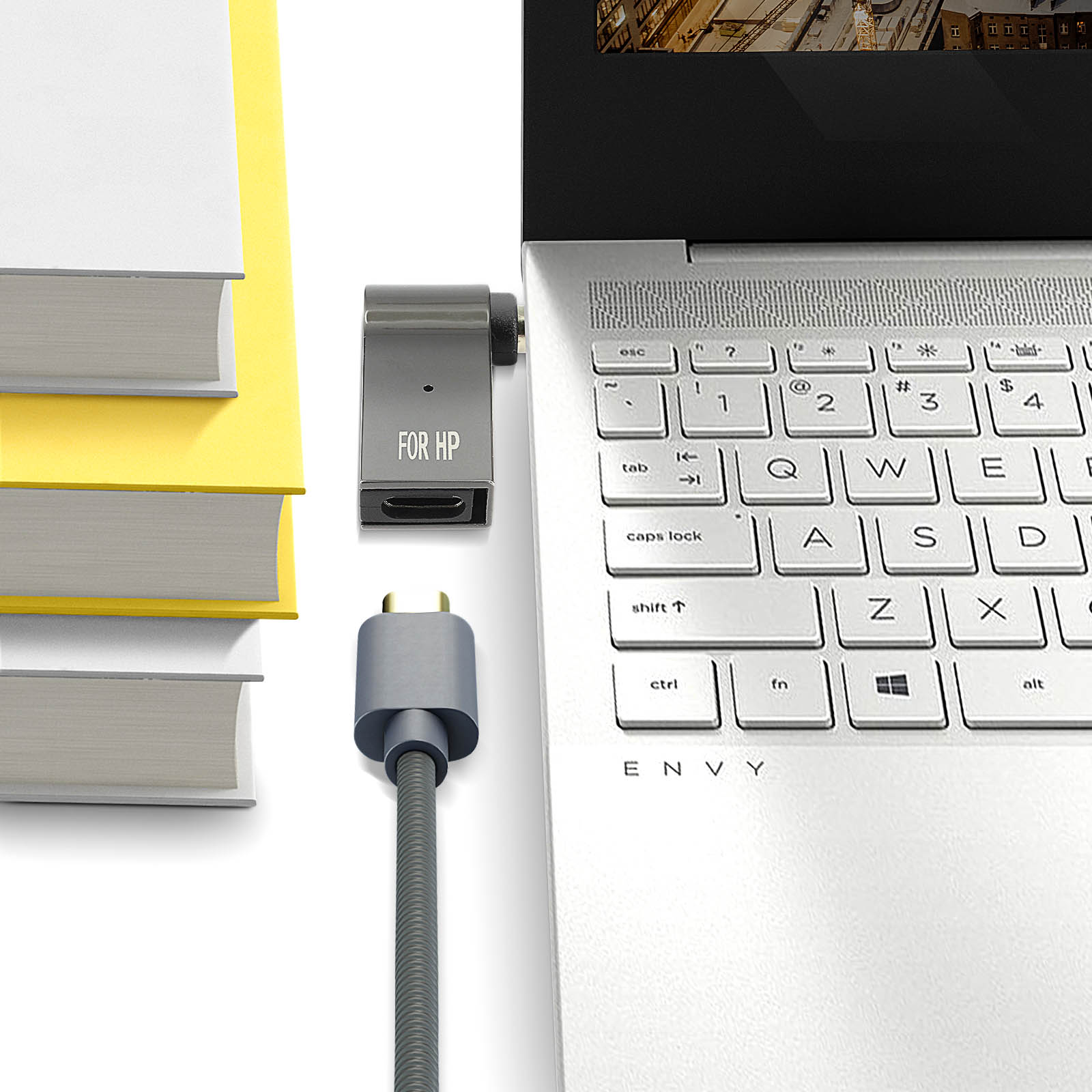 Laptop con adattatore USB-C collegato. Adattatore etichettato 'FOR HP'. Libri sullo sfondo.