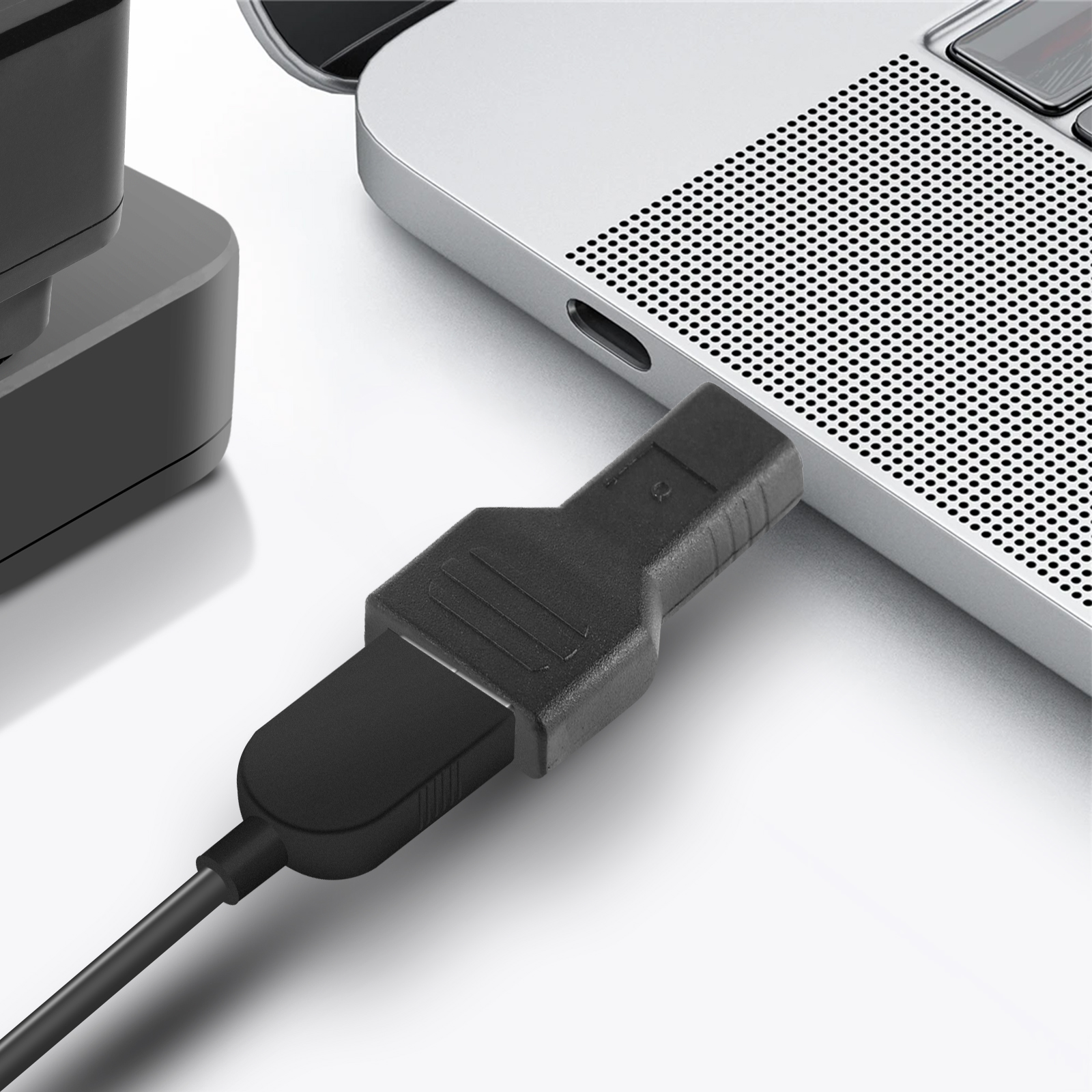 Cavo USB nero inserito in un laptop. Sfondo bianco.