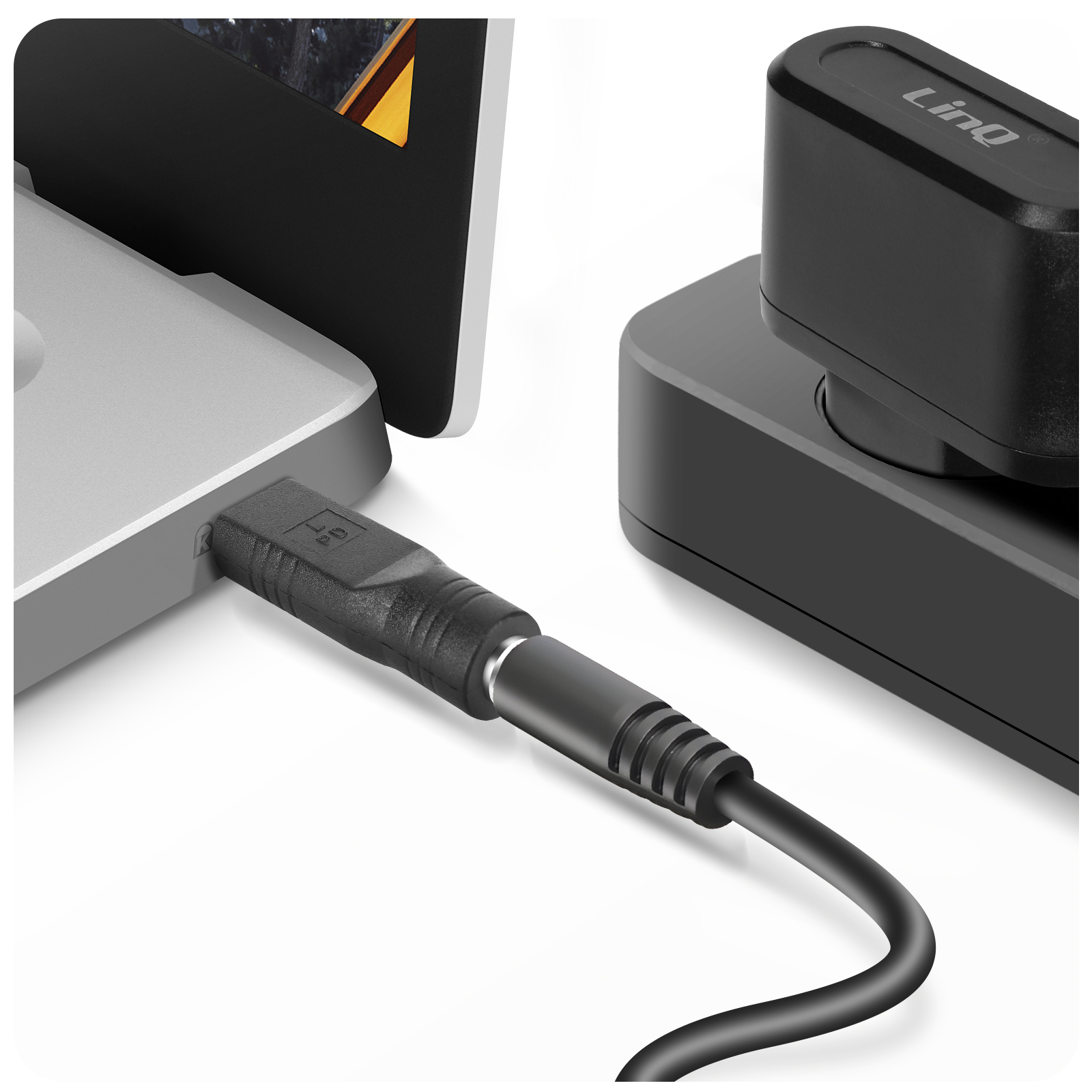 Un cavo nero si collega a un laptop e a un hub nero. L'impostazione è su una superficie bianca.