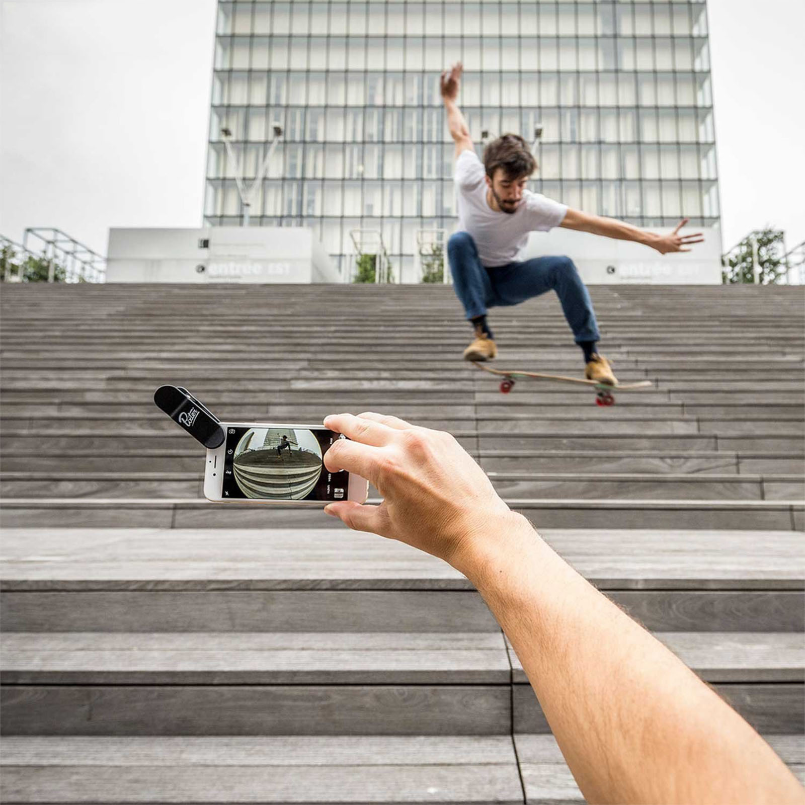 Eine Person filmt einen Skateboarder auf einer Treppe. Der Skateboarder befindet sich in der Luft.
