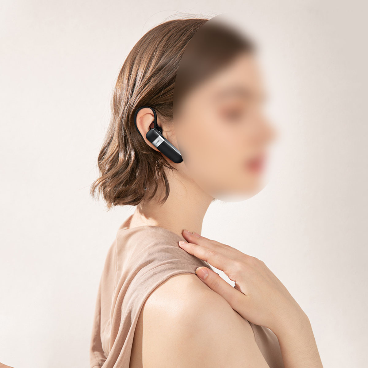 Ein drahtloses Bluetooth-Headset, getragen von einer Frau, schwarzes und silbernes Design.