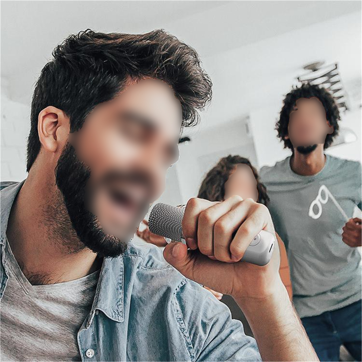 Hombre con barba canta en un micrófono. Dos personas borrosas en el fondo.