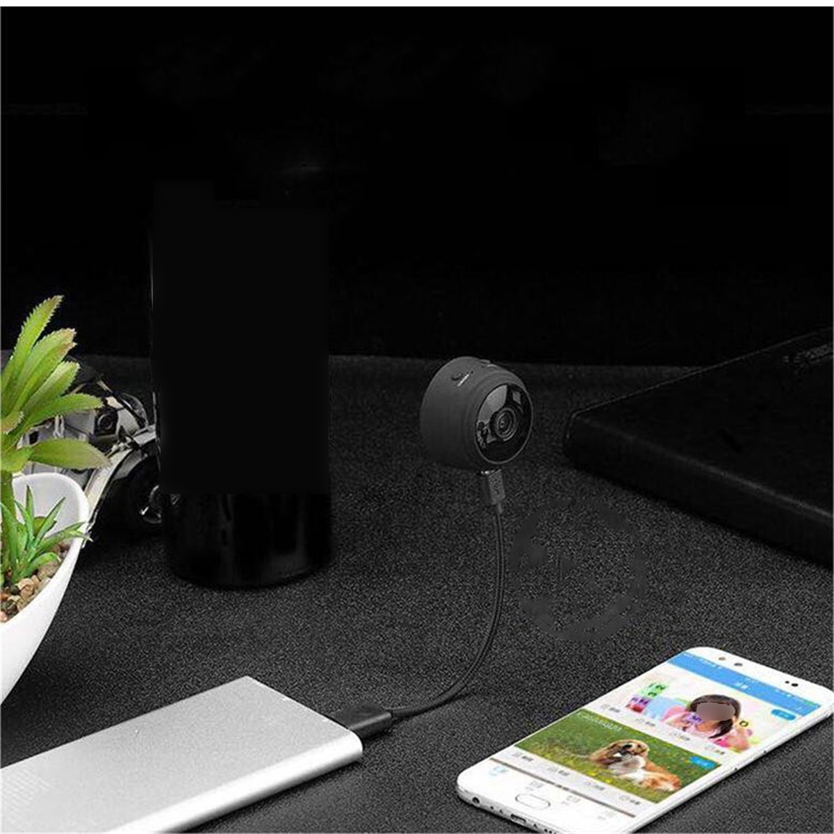 Mini-Überwachungskamera an Powerbank angeschlossen, Smartphone zeigt Live-Feed.