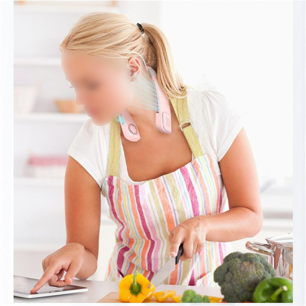 Eine Frau, die einen rosa Nackenventilator trägt, schneidet Gemüse auf einer Theke in einer Küche.