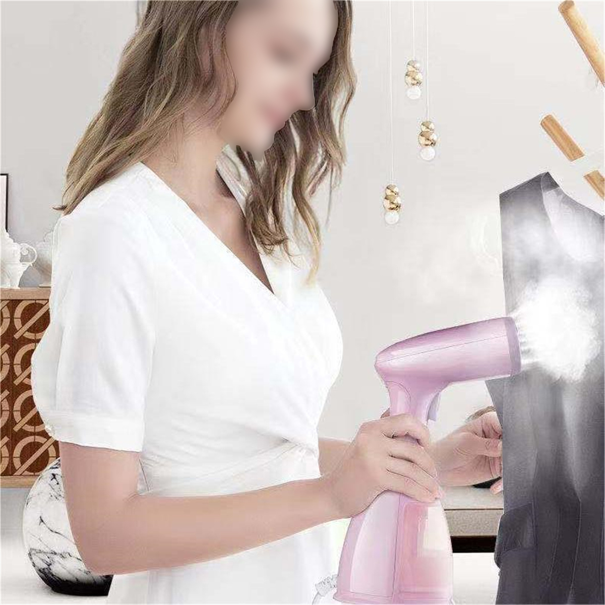 Frau mit rosa Dampfgarer auf dunkler Kleidung. Dampf steigt auf. Hintergrund: Hängelampen und Möbel.