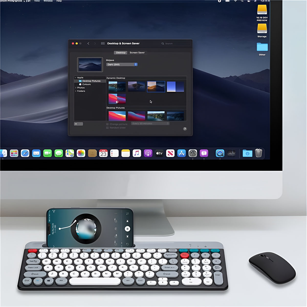 Desktop-Setup mit Monitor, der Bildschirmschoner zeigt, und Telefon auf Tastatur.