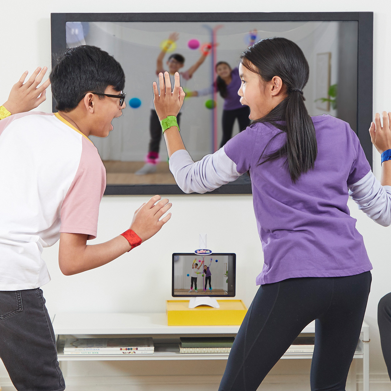 Dwie osoby grają w grę na telewizorze, z tabletem pokazującym grę i bransoletkami.