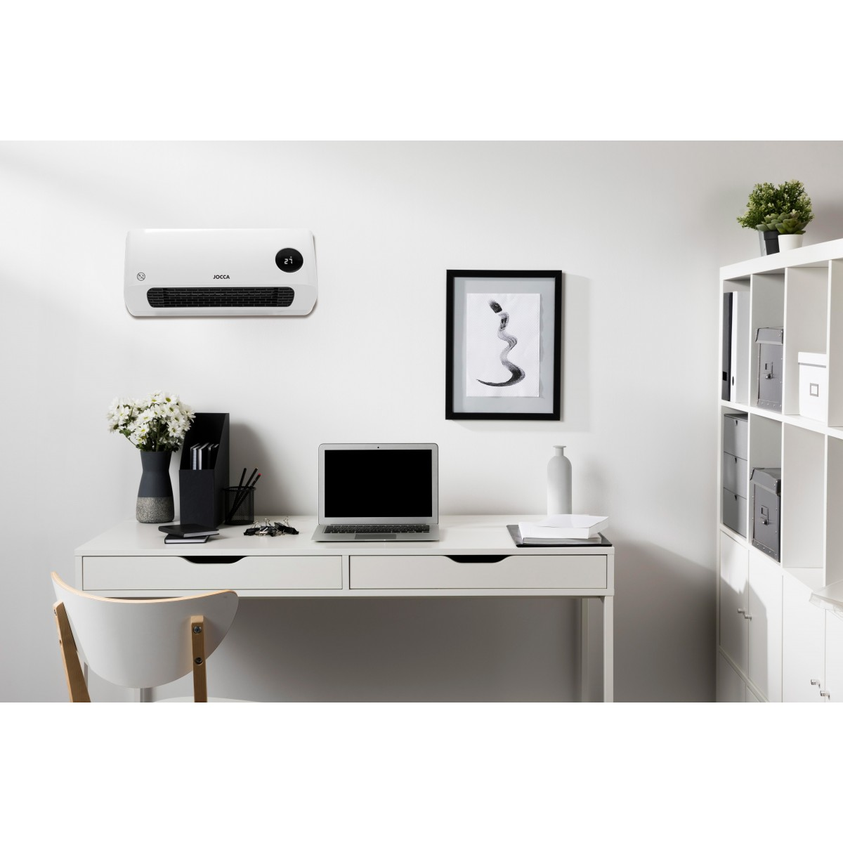 Calentador blanco montado en la pared. Un escritorio, portátil y decoración están en la habitación. Fondo blanco.