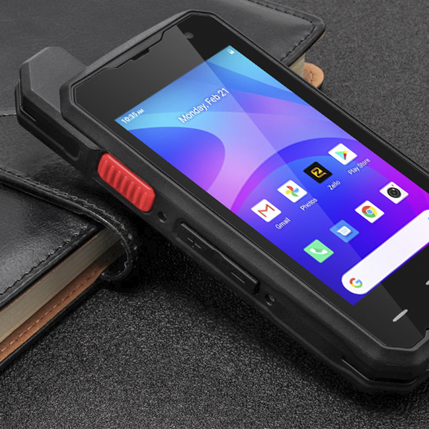 Smartphone nero con pulsante rosso, schermo con app e portafoglio su superficie scura.