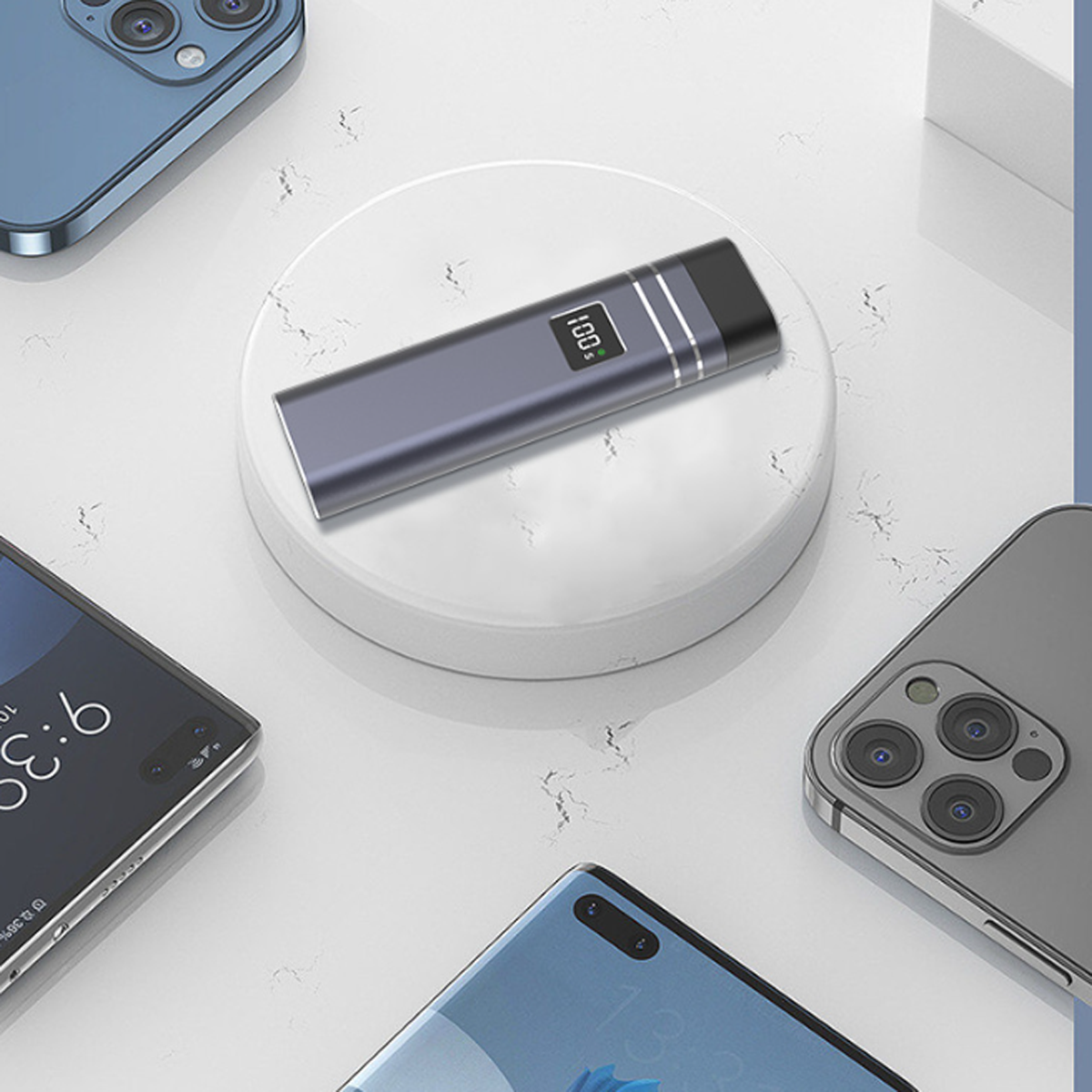 Ein Ladegerät auf einer weißen Plattform, umgeben von mehreren Smartphones auf einer hellen Oberfläche.