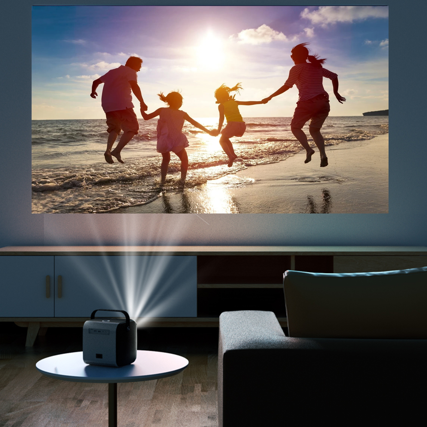 Immagine proiettata sulla parete mostra una famiglia che salta su una spiaggia. Un proiettore su un tavolo emette la luce.