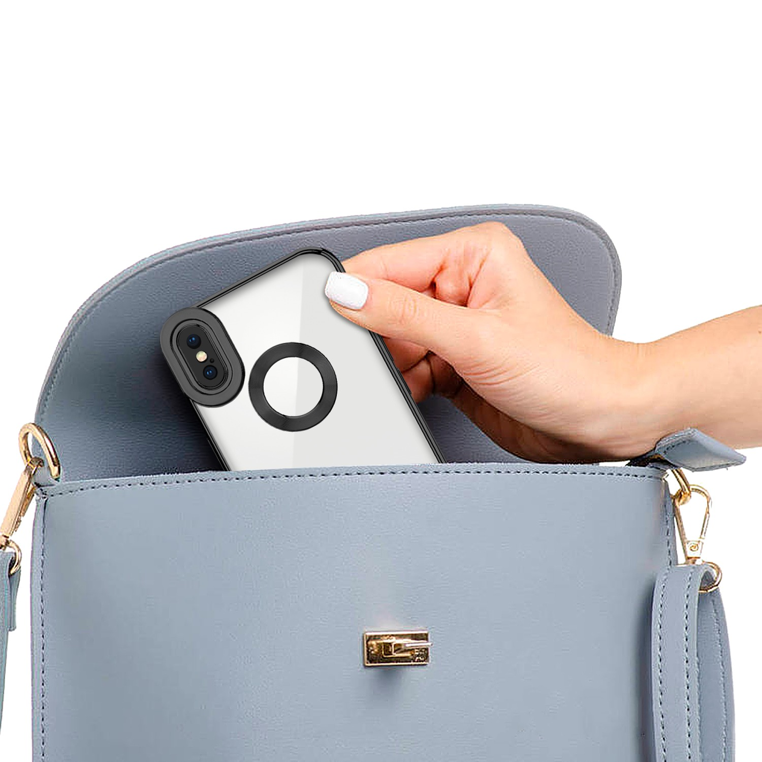 Hand legt ein Telefon mit klarer Hülle in eine blaue Handtasche mit goldenem Verschluss.