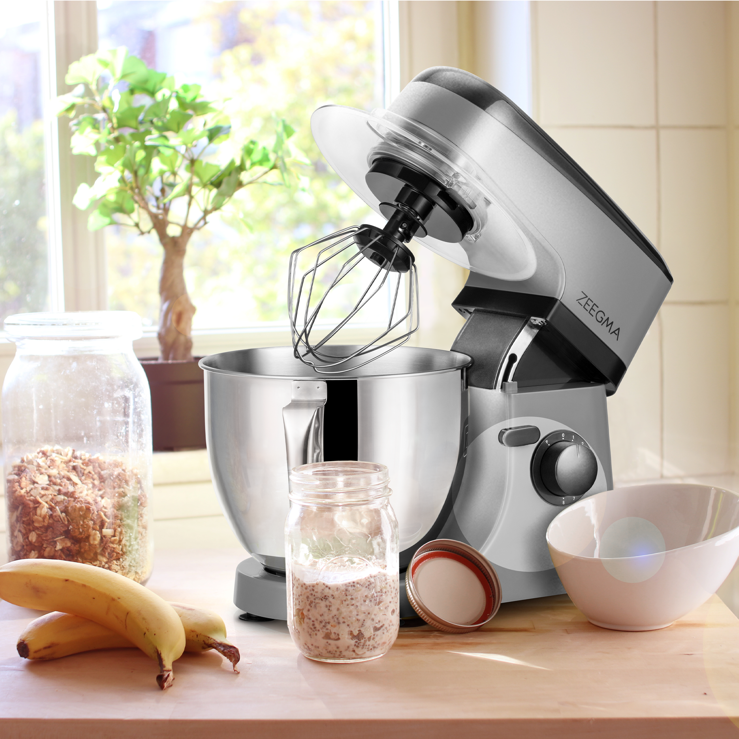 Srebrny mikser stojący ze składnikami na drewnianym stole w pobliżu okna.