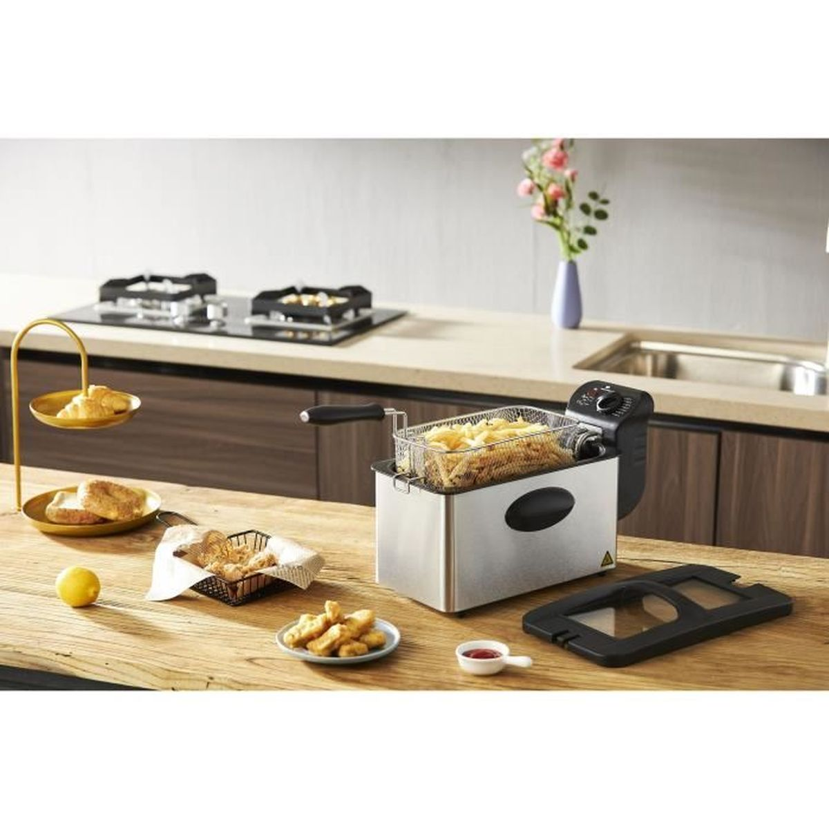 Pommes in Fritteuse, Beilagen, Holztisch, Küchenumgebung, Blumenvase.